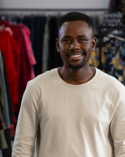 A smiling shop owner at the counter of his clothing store